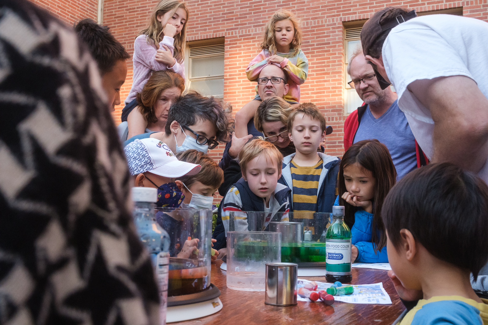 Children and parents watch a tank with colored water spin and demonstrate atmospheric flows.